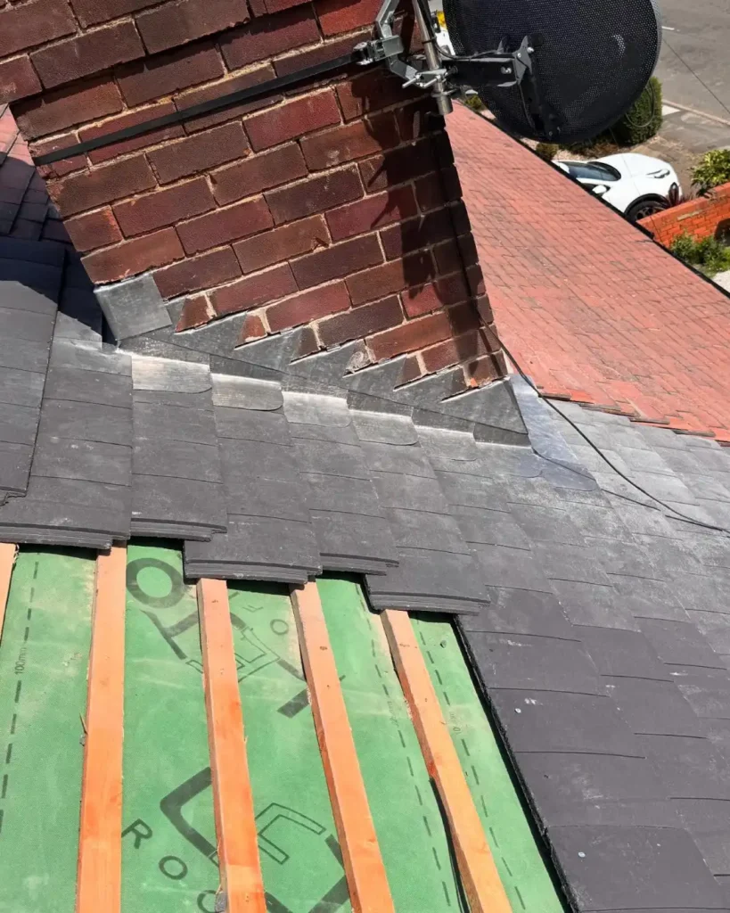 Mid-distance shot of chimney with partially completed roof showing tiles and underlay.