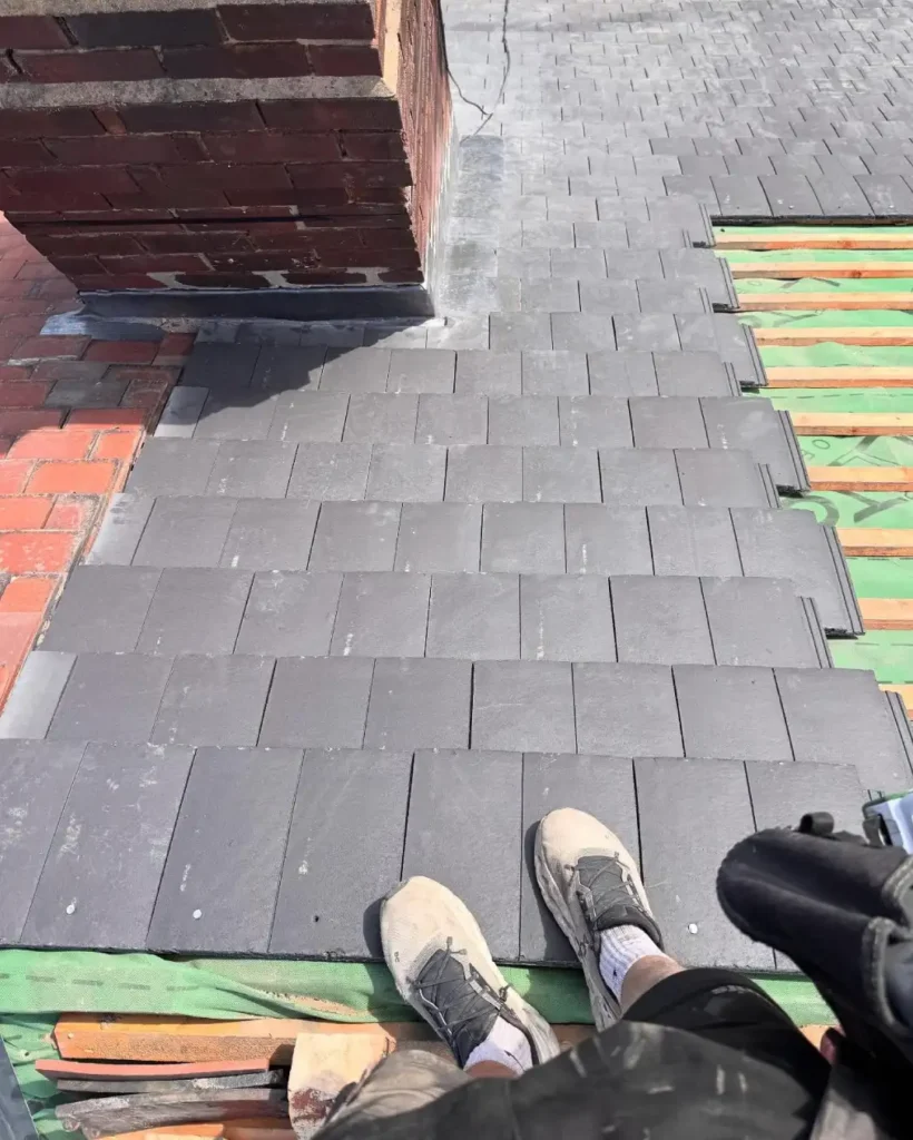 Top-down view near chimney showing tile installation and exposed timber underlay.